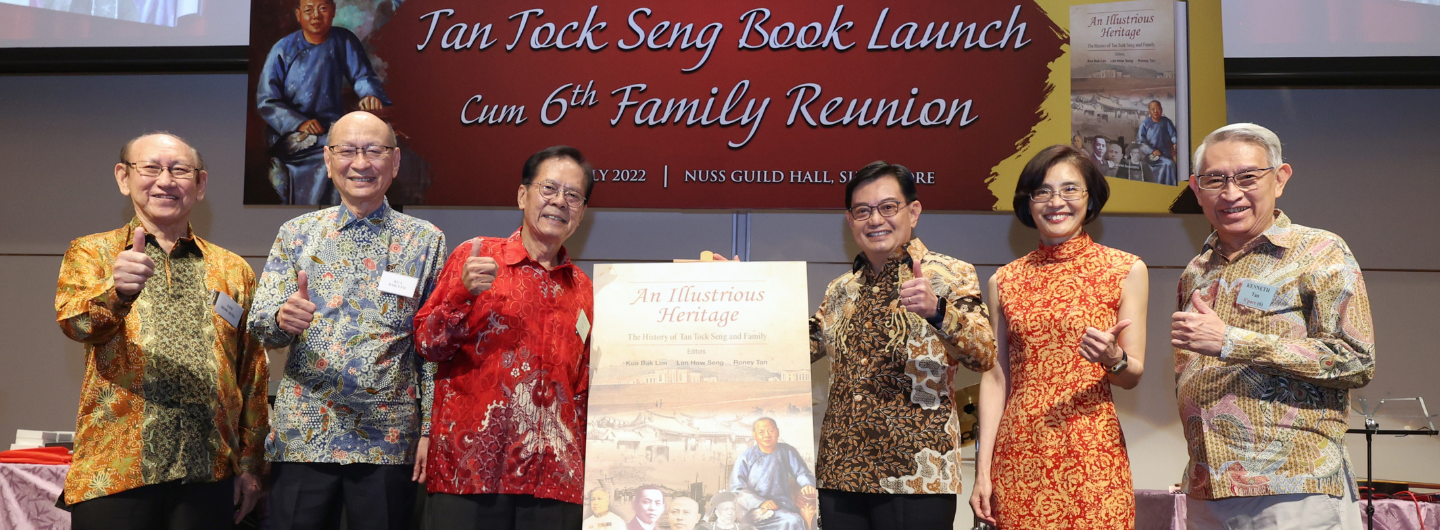 Six people giving thumbs up, holding "An Illustrious Heritage" book at book launch.